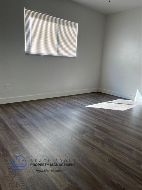 an empty living room with wood floors and a window
